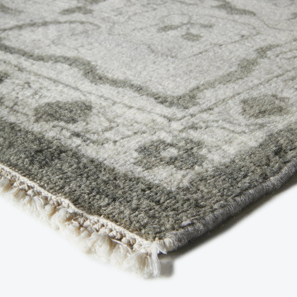 Close-up of a soft, gray rug with fringe and texture.