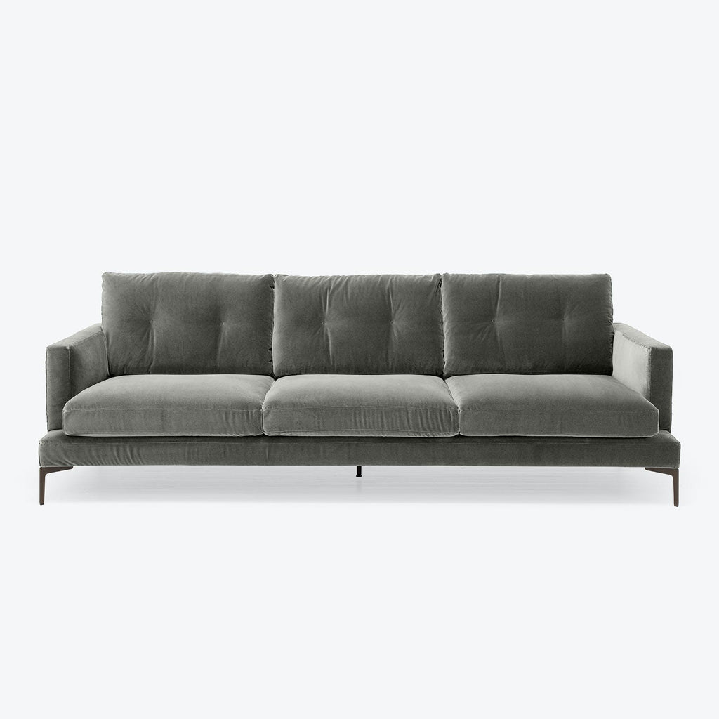Minimalist modern sofa with plush velvet upholstery in dark tones.