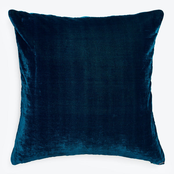Deep blue velvet square pillow exudes elegance against white backdrop.