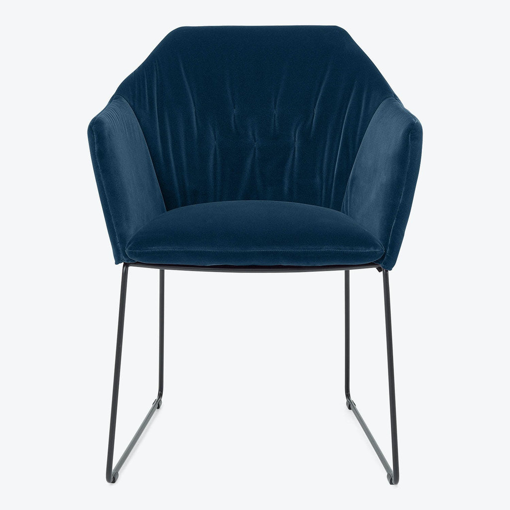 Modern armchair with deep blue velvet upholstery exudes luxurious elegance.