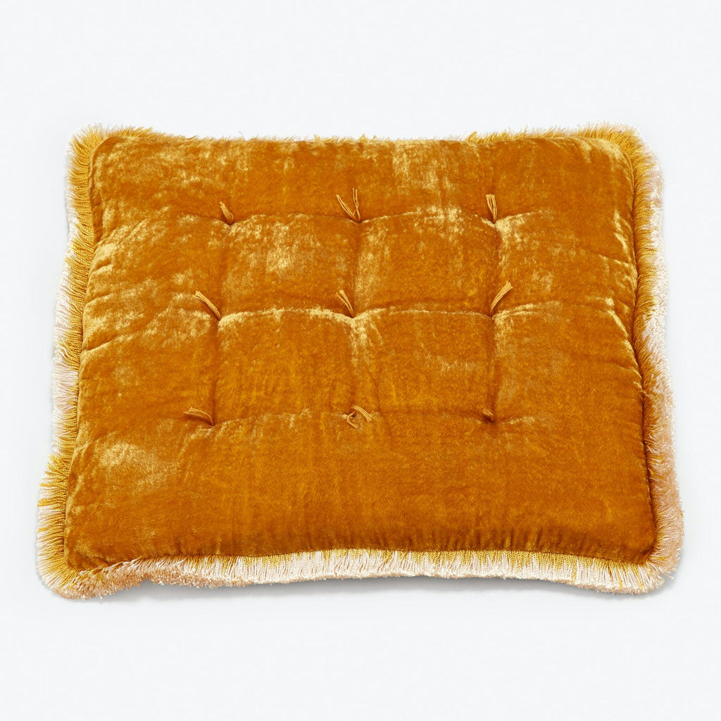 A luxurious golden-yellow velvet cushion with intricate tufted grid pattern.