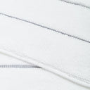 Close-up of white textured fabric with dark stitches and zipper.