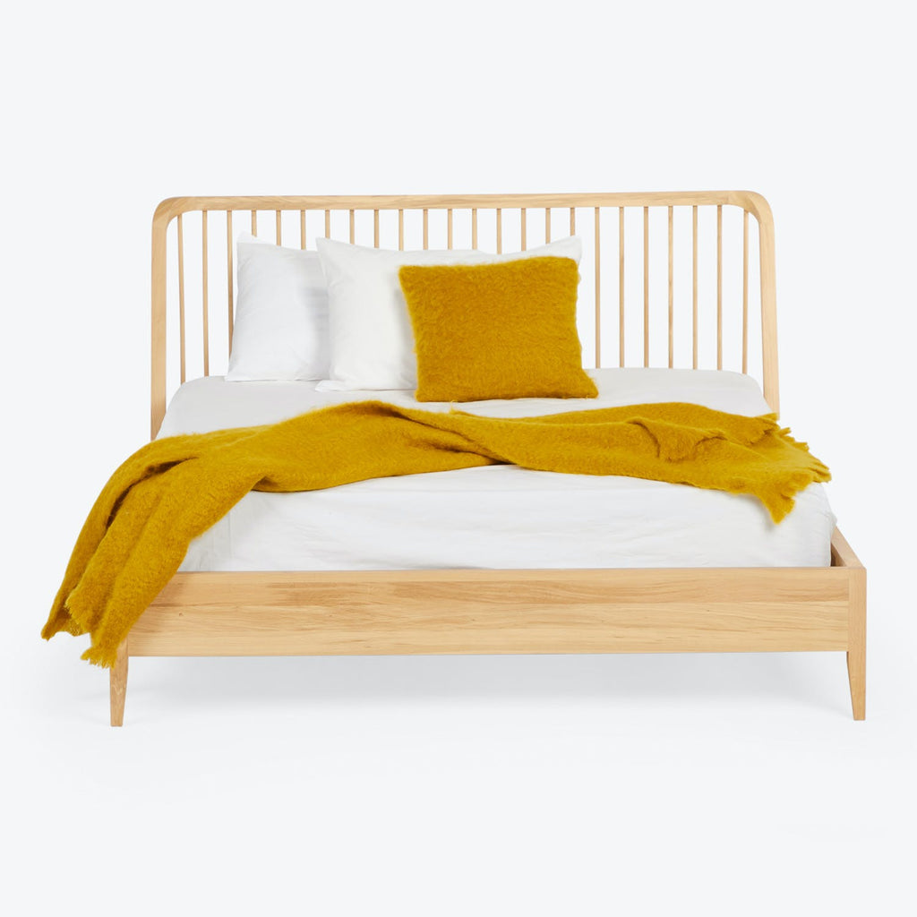 Modern wooden bed dressed in white bedding with mustard accents.