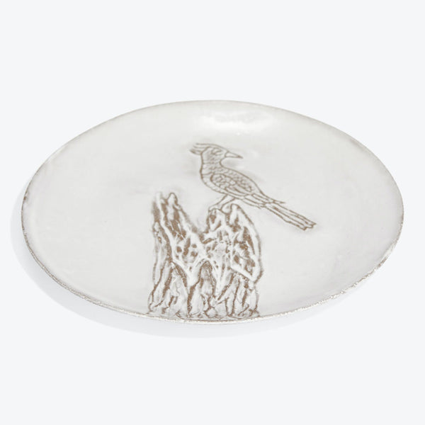 Handcrafted white plate with embossed bird illustration and textured surface.