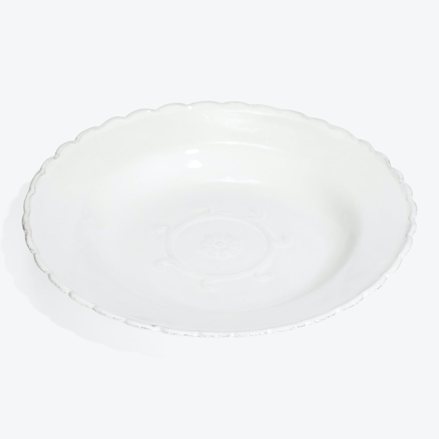 White ceramic plate with scalloped edge and embossed floral pattern.