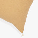 Cozy mustard-yellow cushion with textured surface and delicate tassel.