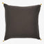 Square-shaped dark pillow with woven texture and gold tassel embellishments.