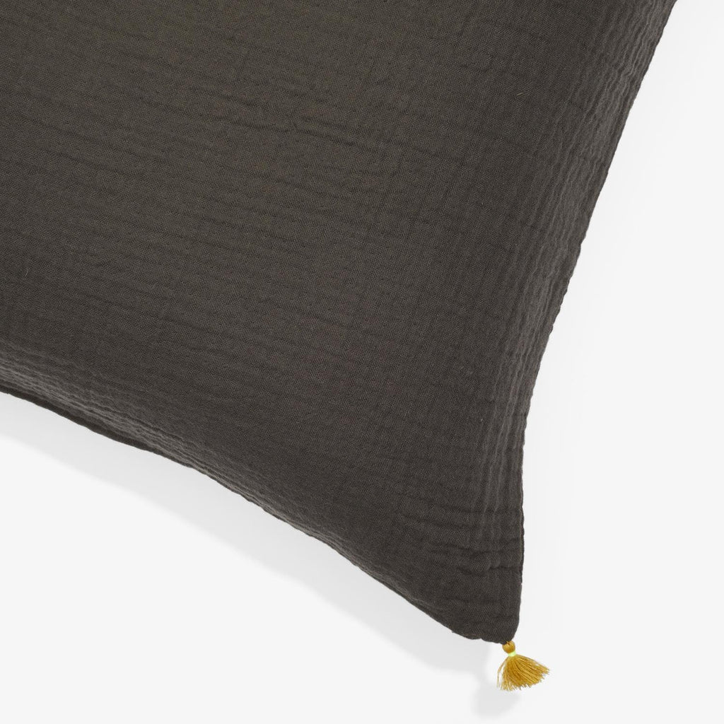 Close-up of textured dark cushion with gold tassel detail.