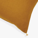 Close-up of a mustard yellow textured pillow with tassel detail.