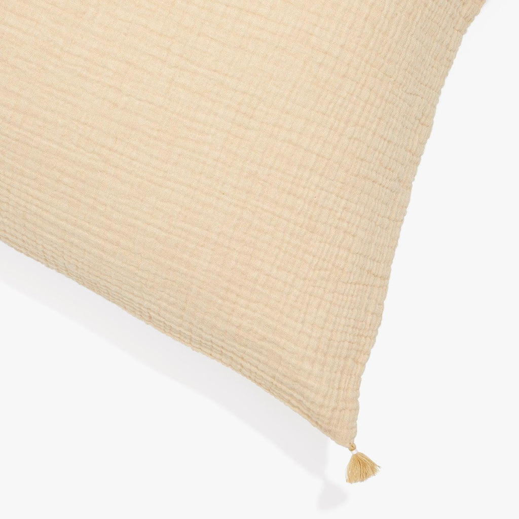 Close-up of a textured cream cushion with a tassel attachment.