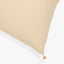 Close-up of a textured cream cushion with a tassel attachment.