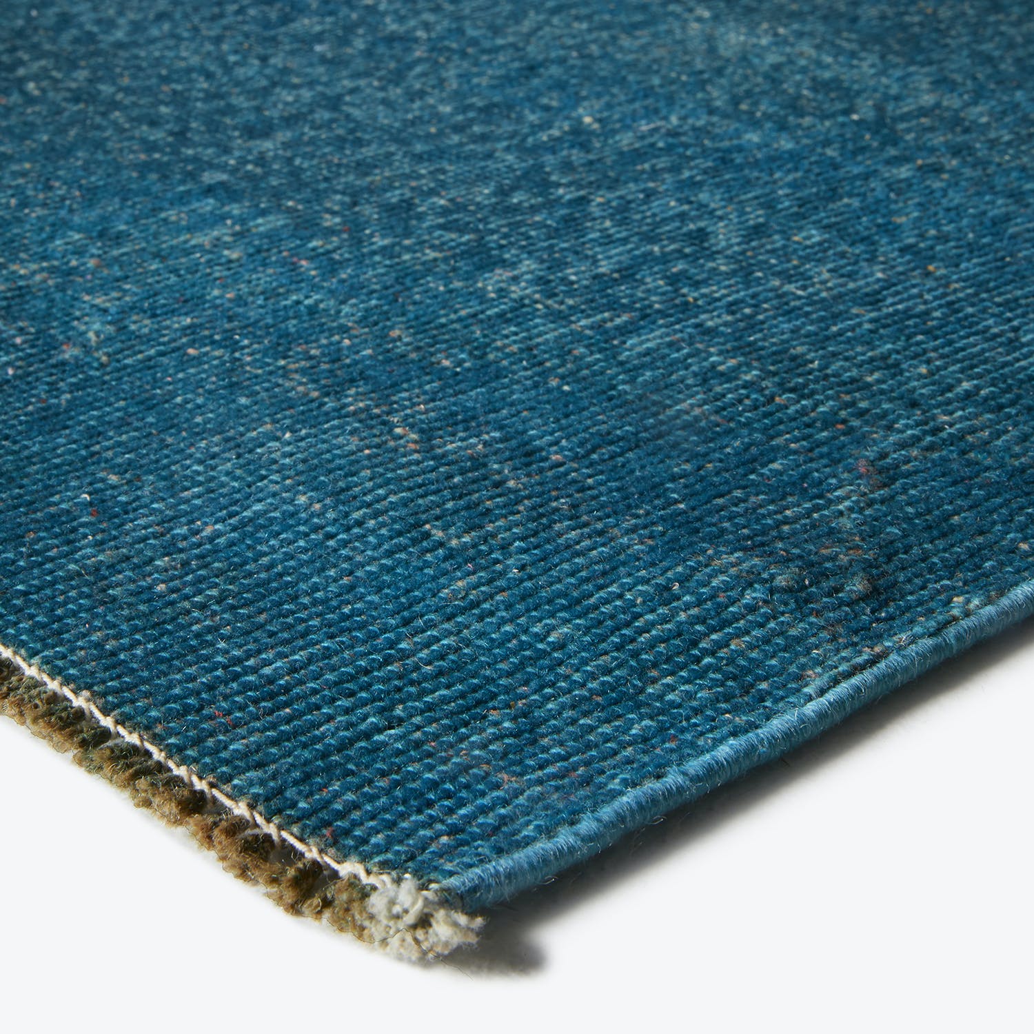 Close-up of a sturdy blue carpet with frayed edges.