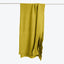 Green fabric hangs smoothly over a white background, softly draping.