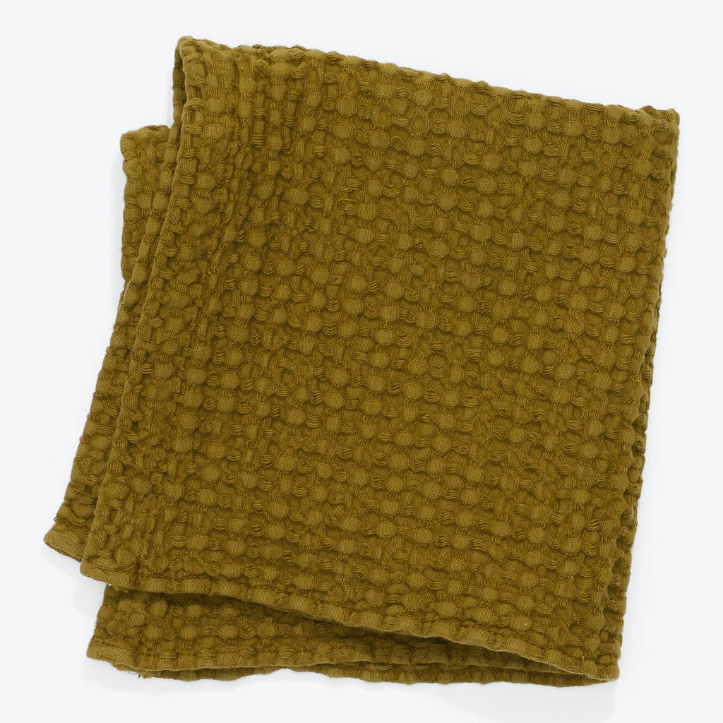 Olive green blanket with embossed, three-dimensional pattern and plush texture.