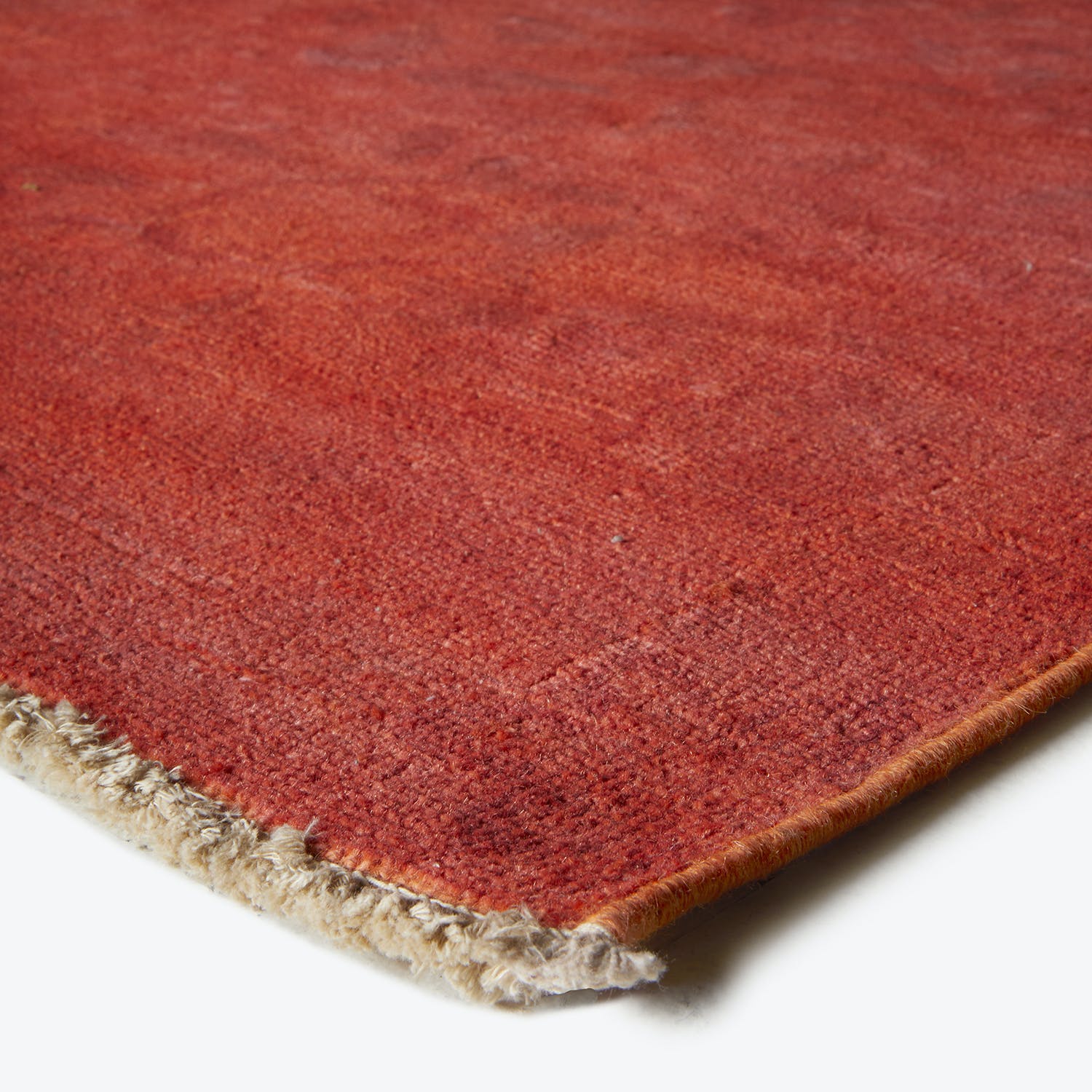 Close-up of red carpet with soft texture and frayed edge.