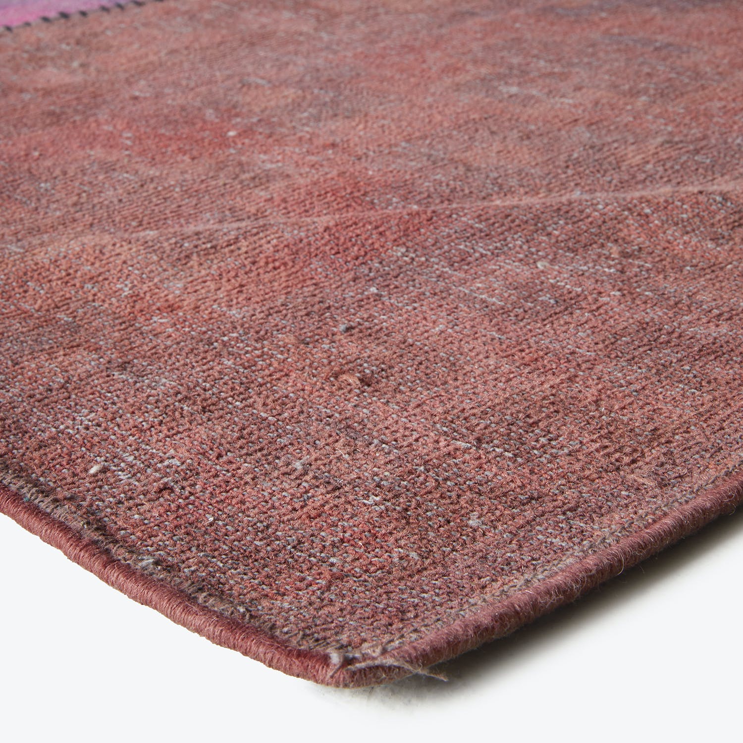 Close-up of a used pink and red area rug.