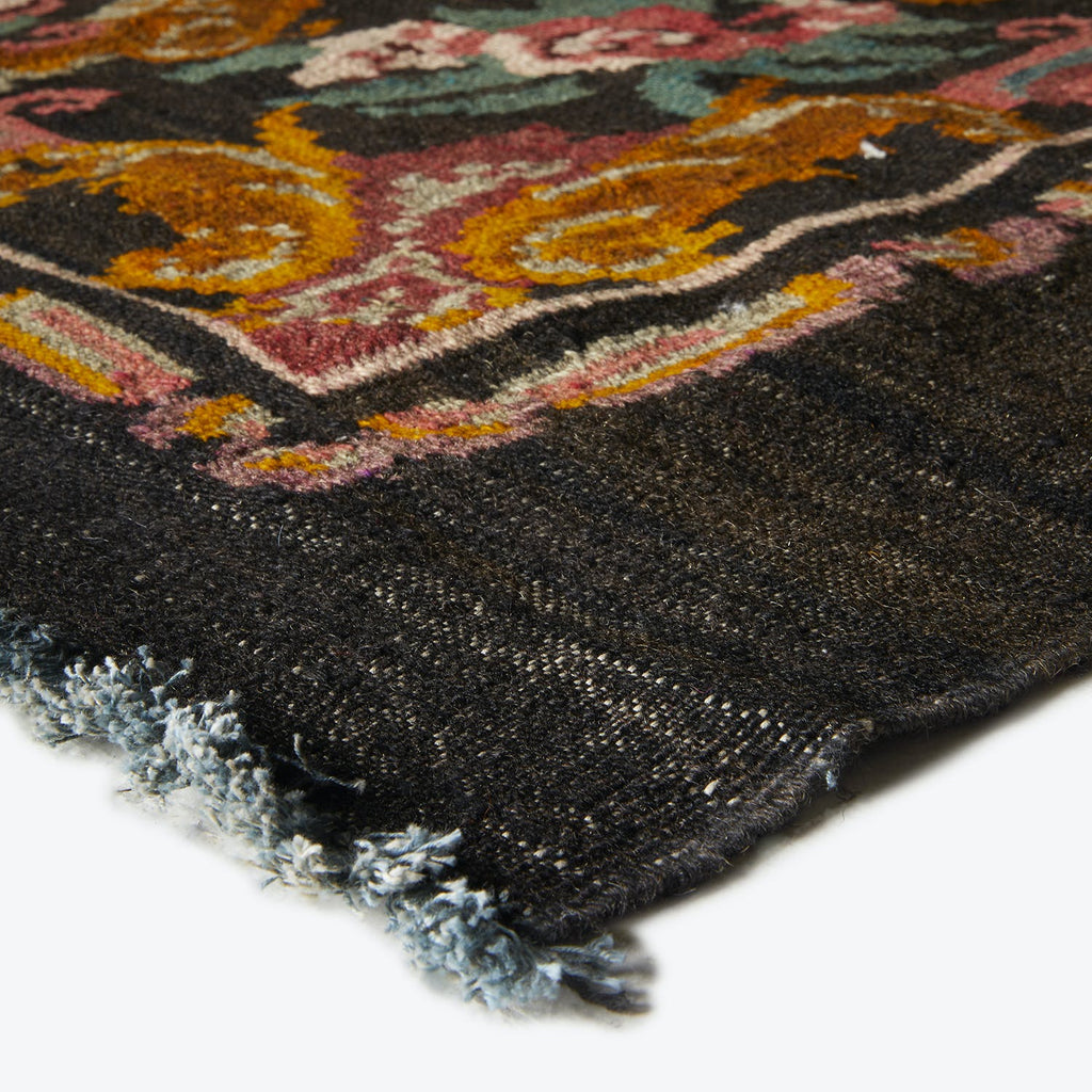 Close-up of a colorful, ornate rug with frayed edges indicating wear.
