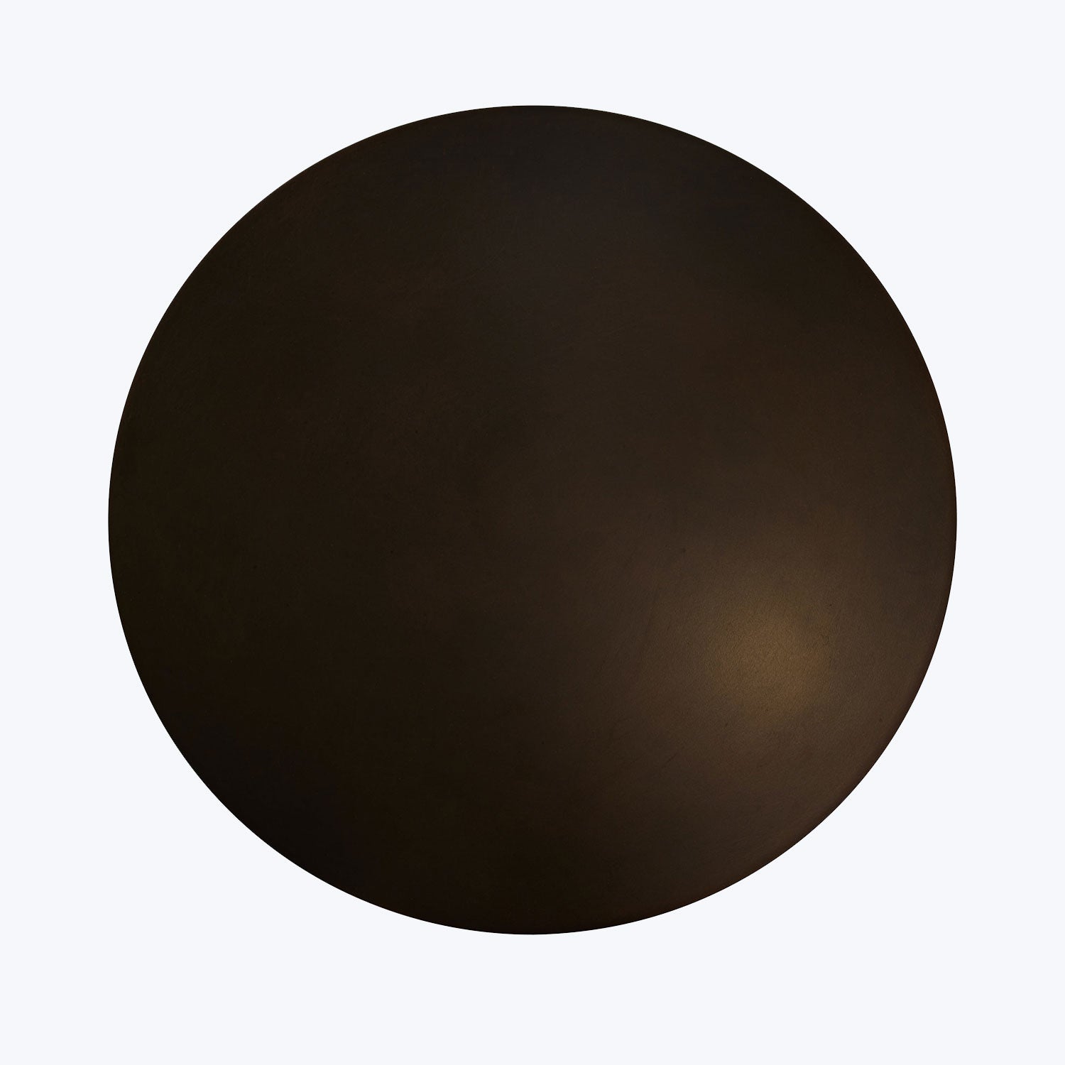 Mysterious dark circular object against a lighter background, open to interpretation.