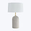 Contemporary table lamp with concrete-like base and minimalist design.