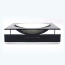 Minimalist tabletop accessory with sleek design, featuring a clear concave element beneath a raised platform. Designed by Alexandra Von Furstenberg.