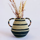 Handcrafted woven basket adorned with striped pattern holds dried flora.