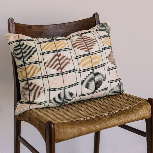 Wooden chair with woven seat and decorative geometric pattern pillow.