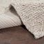 Close-up view of plush textured rug on wood floor.