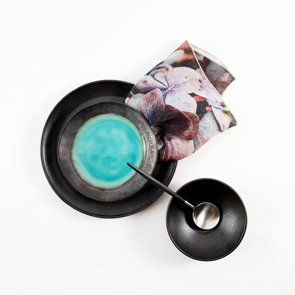 Vibrant blue liquid in a black bowl with floral napkin
