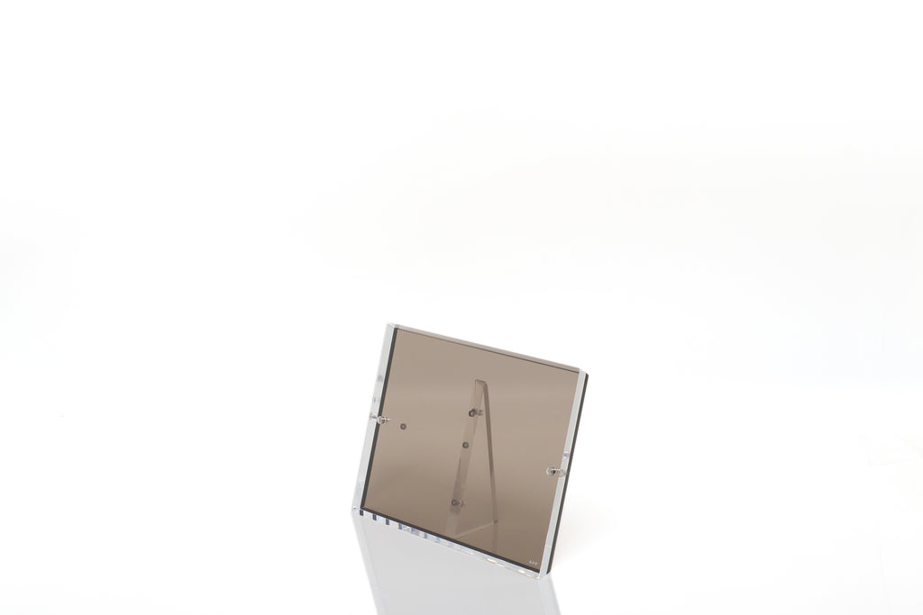 Minimalist tabletop mirror with metallic frame reflects a glossy surface.