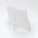 Modern acrylic frame with metallic hinges stands freely, exuding simplicity.