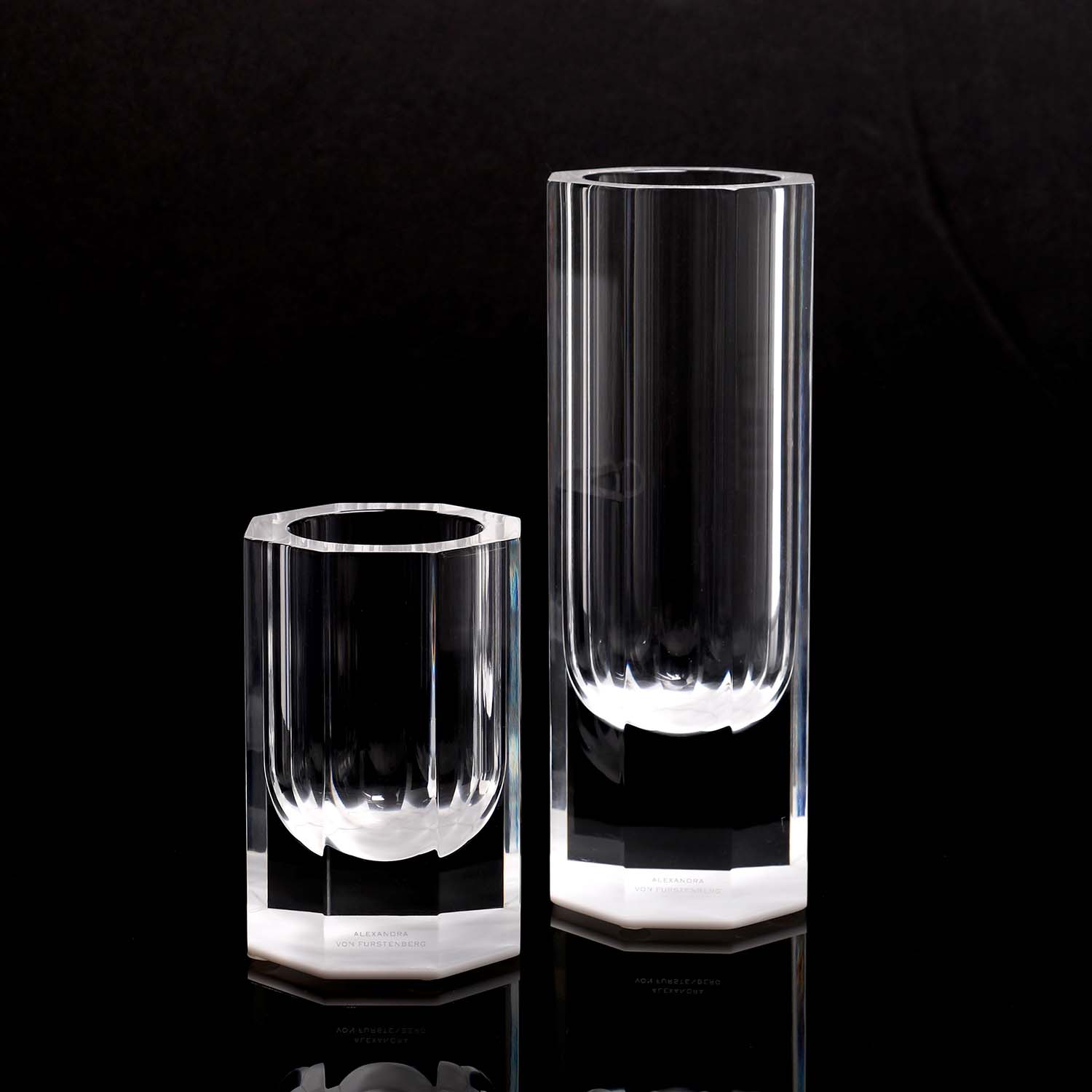 Two elegant glass cylinders with mirror-like reflection and sleek design.