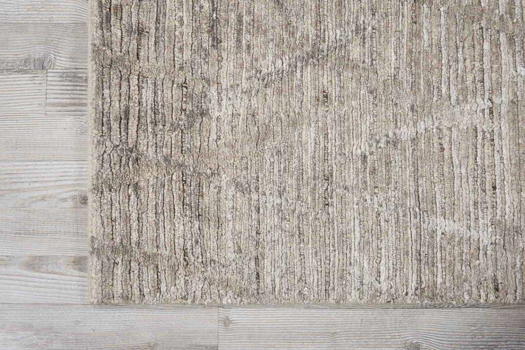 Close-up of a neutral, ribbed carpet on a wooden floor.