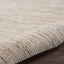 Close-up view of textured carpet with rolled edge on wooden floor.
