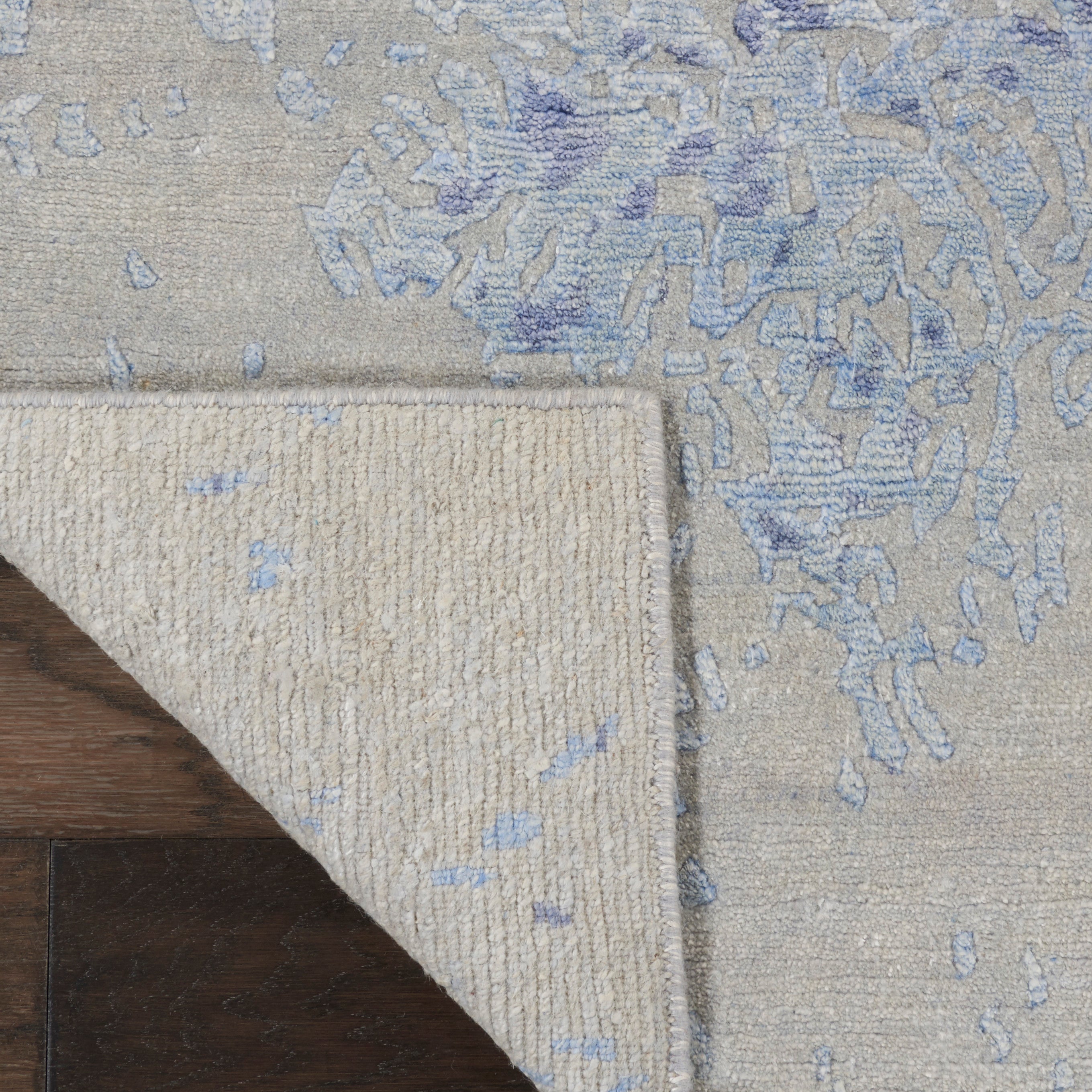 Close-up of high-quality, modern rug with abstract blue design on wooden floor.