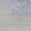 Close-up of beige denim fabric with faded blue speckles and streaks.