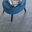Modern round ottoman with blue upholstery on patterned carpet.