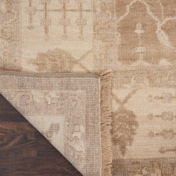 Close-up view of a cream textured area rug on wooden floor.