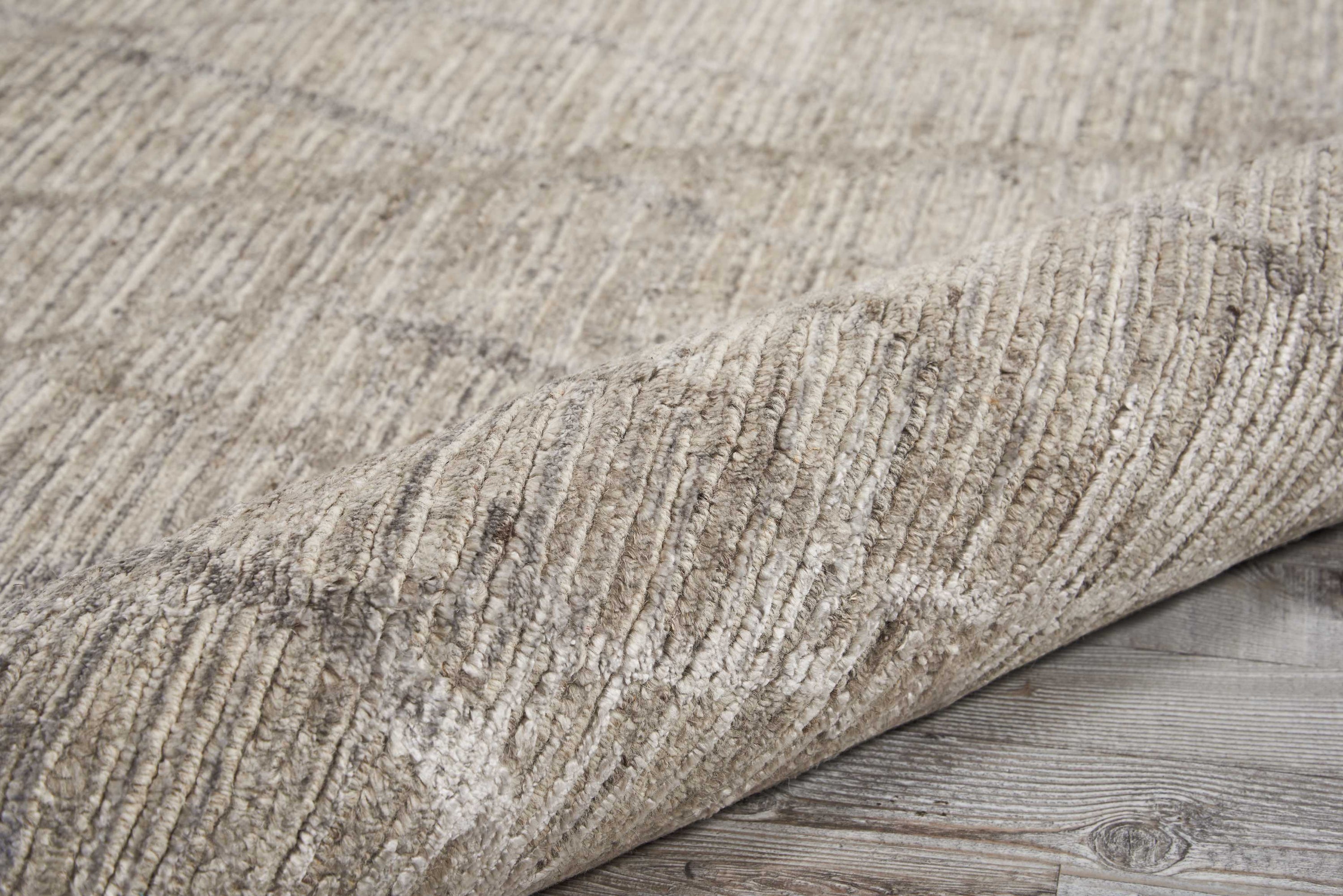 Close-up of textured fabric rug on rustic wooden floor.