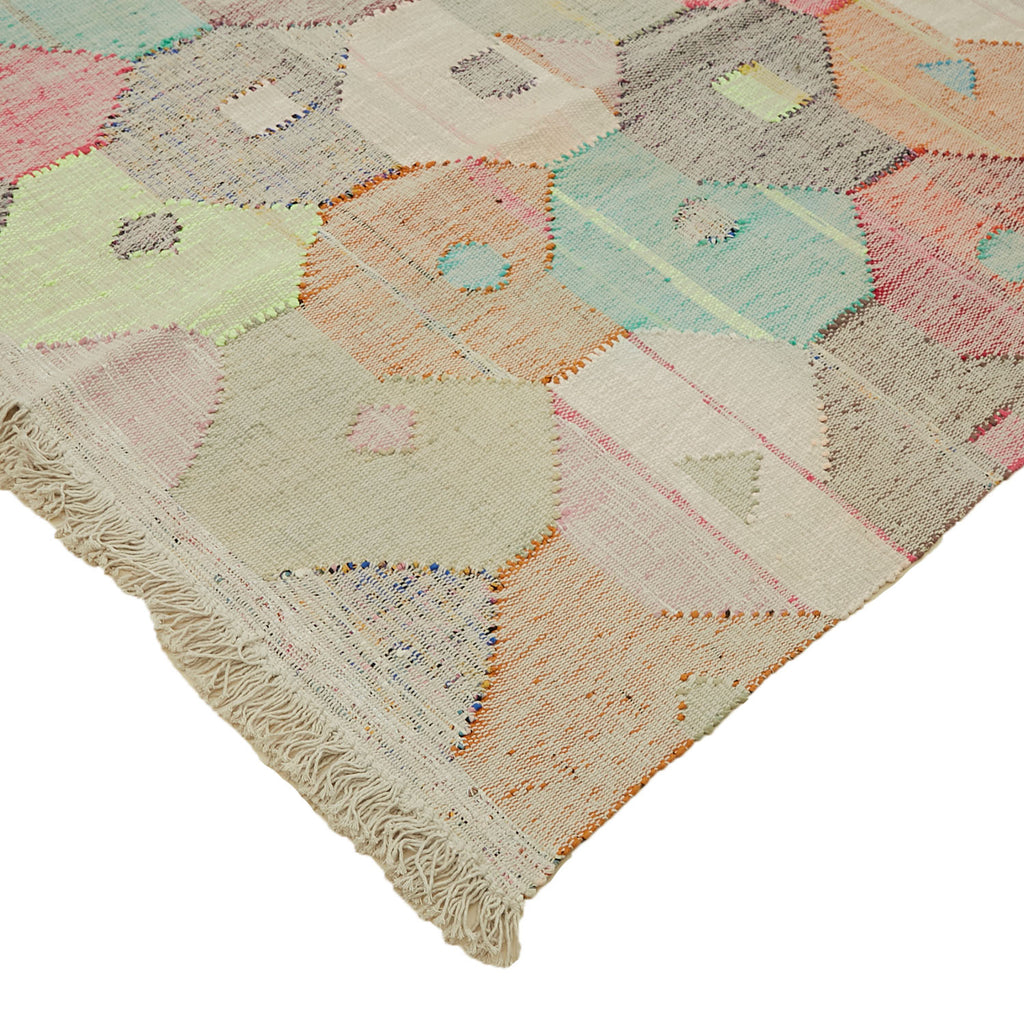 Artisanal patchwork rug featuring geometric shapes in pastel colors.