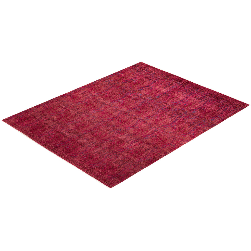 Perspective angle captures textured diamond-shaped area rug in shades of pink and red on a white background.