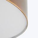 Close-up of a cylindrical object with a matte white top and metallic bottom.