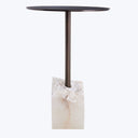 Contemporary side table with dark round top, metallic support, stone base.