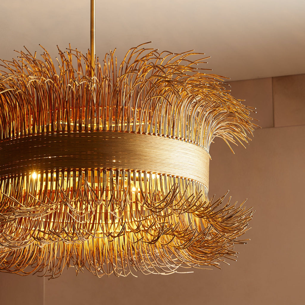 An elegant chandelier with golden rods illuminating a luxurious room.