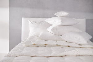 Simply Down Luxury Bedding including pillows, topper, and down comforter on white bedframe