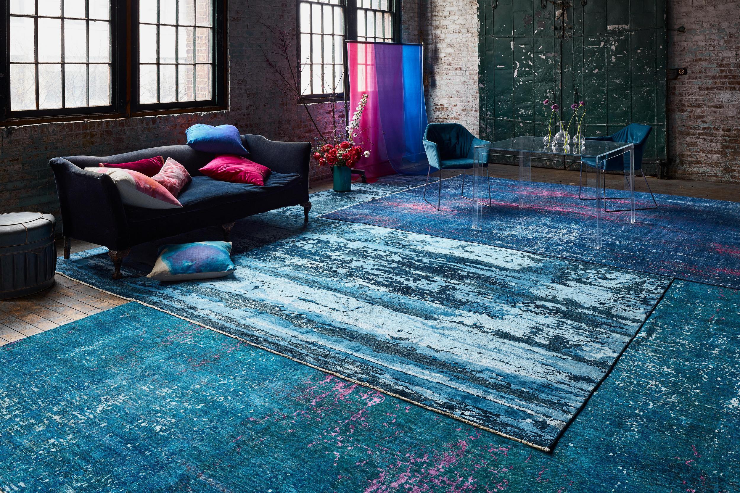 colorful blue rugs in loft living room with couch and large windows