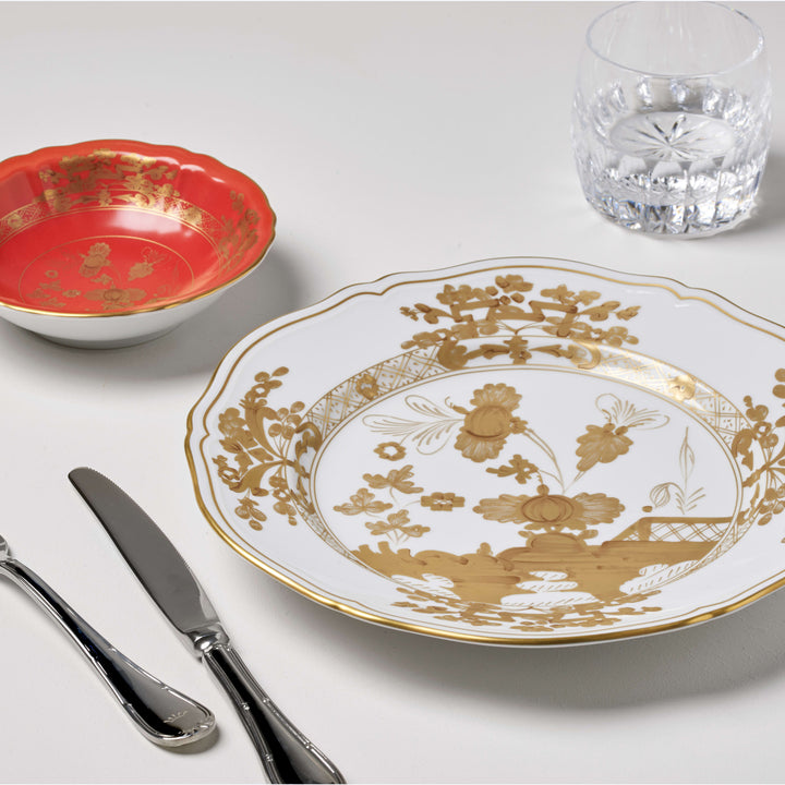 Elegantly set table with ornate plate, shiny utensils, and glass.