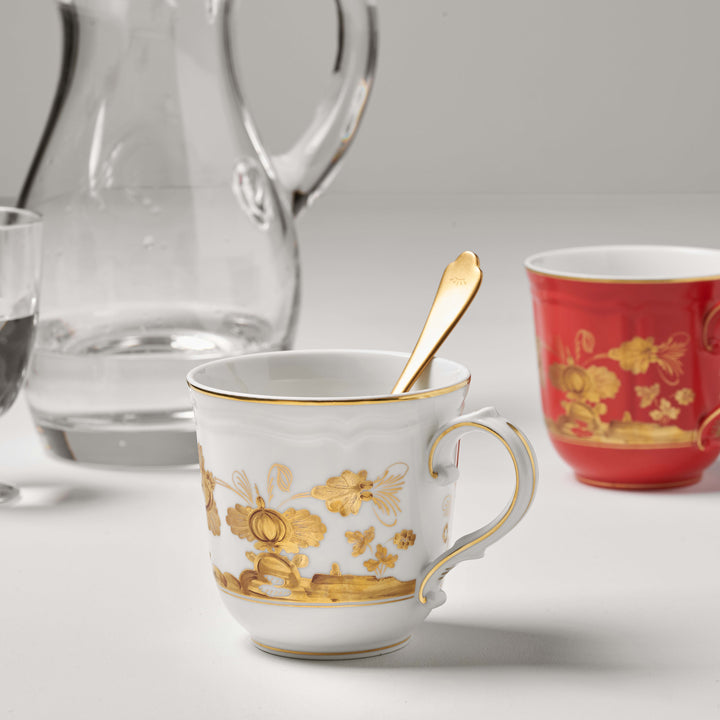 Elegant white teacup with gold floral patterns, surrounded by glassware.