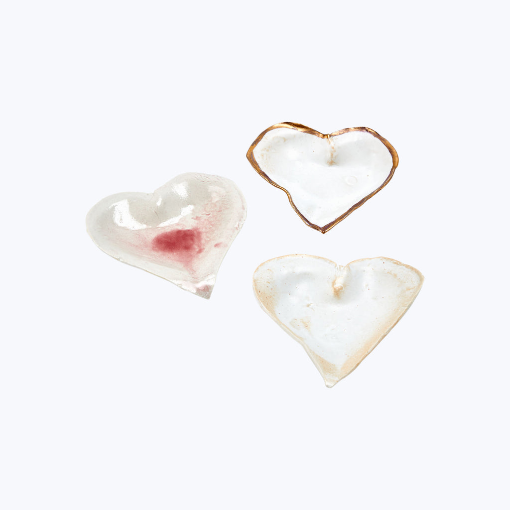 Handcrafted ceramic heart-shaped objects with translucent and rustic appearance.