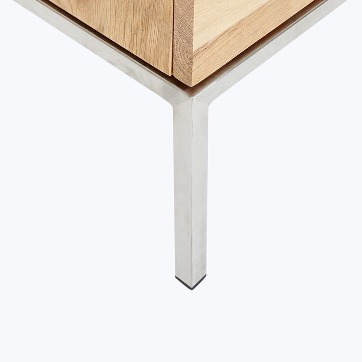 Close-up of modern wooden table corner with sleek metallic leg.