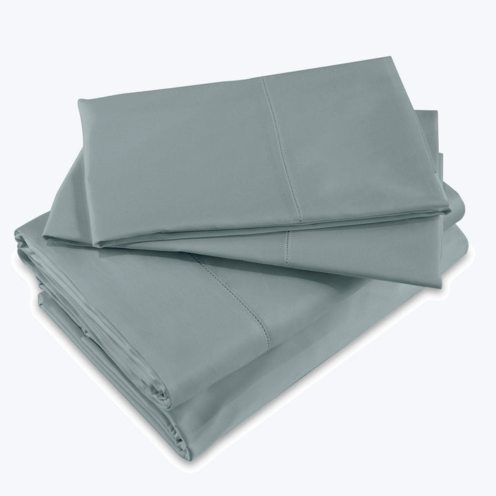 Neatly folded soft green bed sheets, pillowcases in varying sizes.